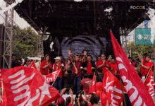 Fotografía del mitin de inicio de campaña electoral del partido FMLN. En un tarima, al centro, se encuentra el candidato presidencial Manuel 'El Chino' Flores y los dirigentes del partido. Abajo, los militantes alzan banderas del partido.