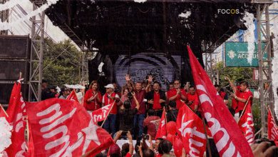 Fotografía del mitin de inicio de campaña electoral del partido FMLN. En un tarima, al centro, se encuentra el candidato presidencial Manuel 'El Chino' Flores y los dirigentes del partido. Abajo, los militantes alzan banderas del partido.